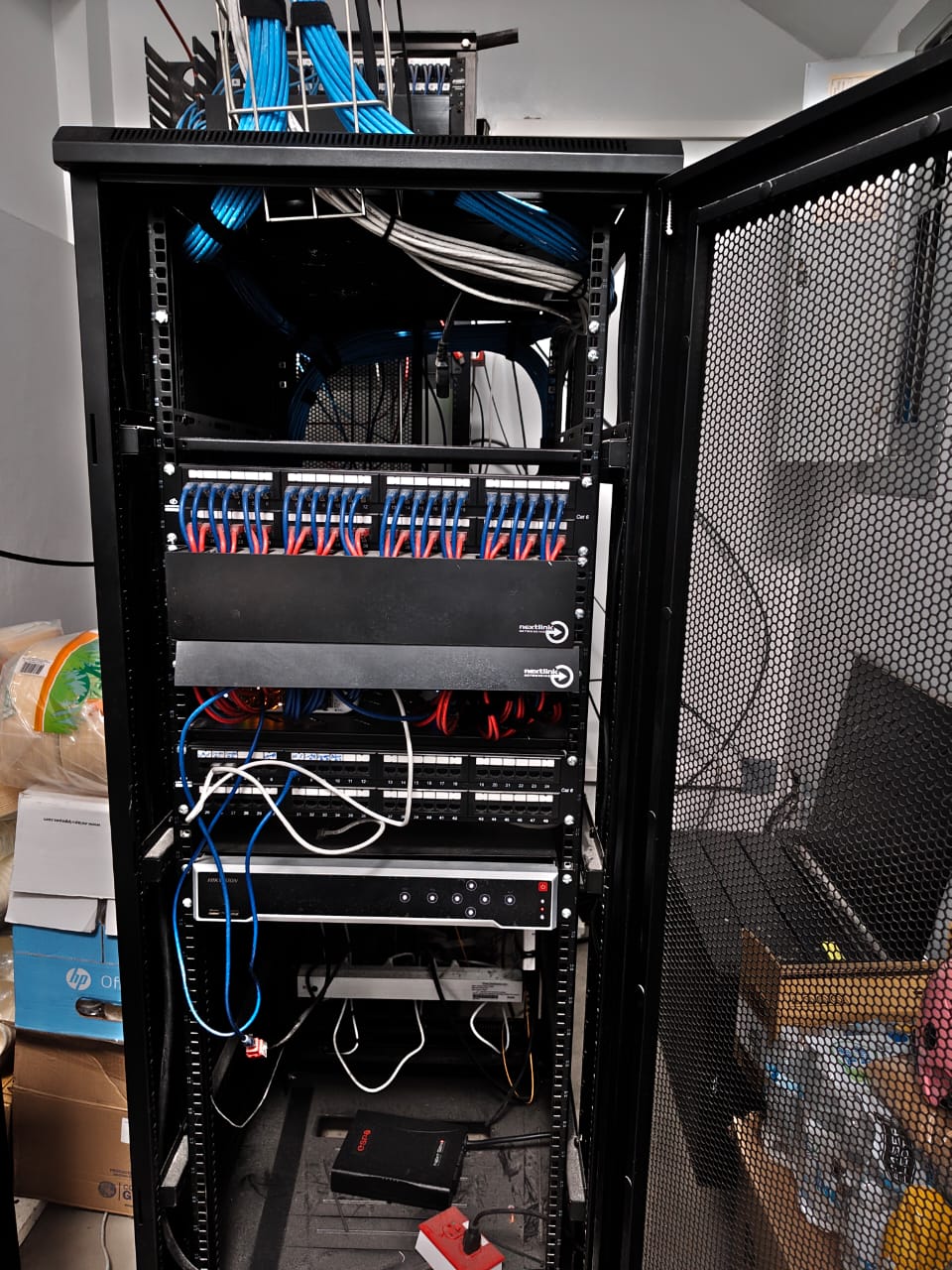Rack de comunicaciones con patch panels, equipos de red y cableado ordenado